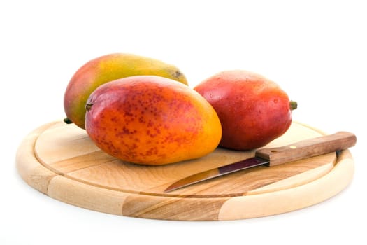 Ripe juicy mangoes on a wooden cutting board on a white background