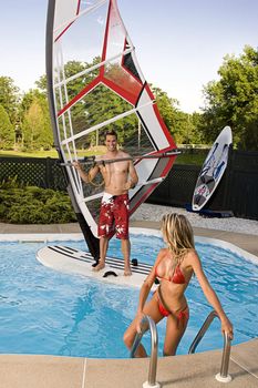 Windsurfer in a pool with a women in bikini coming out of the water