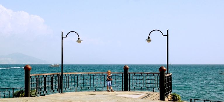 happy young boy looking horizon and dreaming on quay