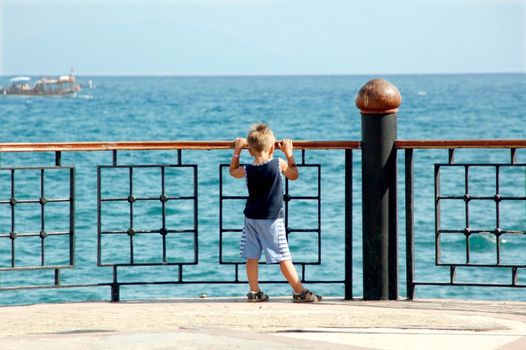 happy young boy looking horizon and dreaming on quay