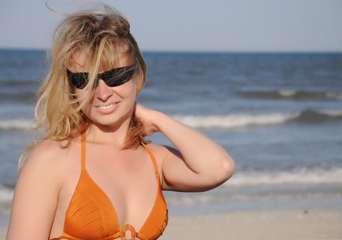 young woman wearing a sunglasses reflecting the beach

