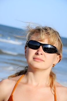 young woman wearing a sunglasses reflecting the beach. sun and an umbrella