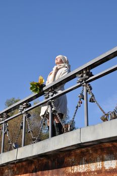 woman sunshines enjoys sunlight on bridge and keeps maple bouquet in hand
