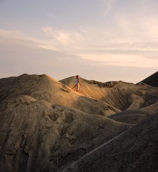 young man go up in sand desert in sundown