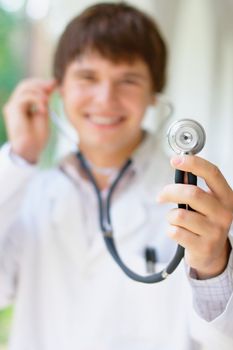 Close-up portrait of a smiling young doctor holding a stethoscope