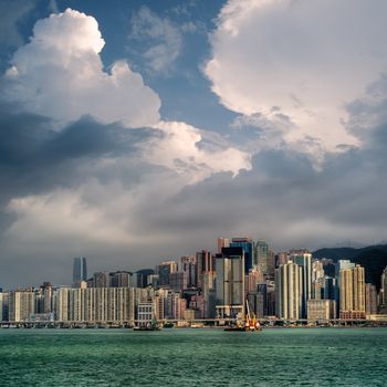 Cityscape with blue sky and white clouds near ocean in Hong Kong.