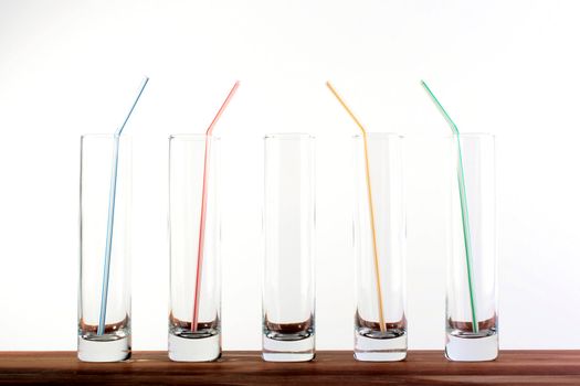 Five high narrow glasses, in four straws for a cocktail.