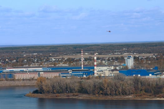 Industrial autumn landscape on the river with flying helicopter