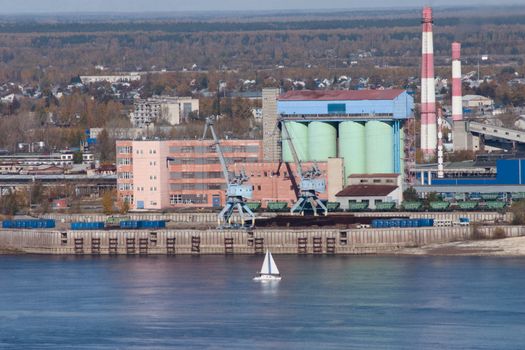 The yacht on the autumn river against an industrial city district