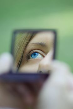 Female eye reflected in a mirror, removed in a sunny day