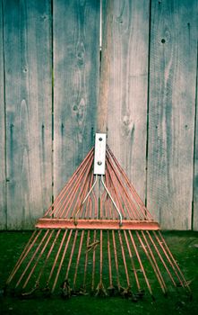 Used old flexible fork rake propped against a weathered gray wooden fence