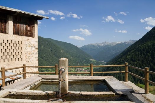 panoramic view of Pejo valley with an old public wash tube on foreground