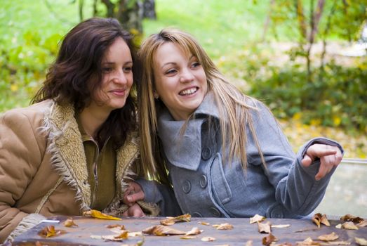 two beautiful woman sitting on table and pointing with finger