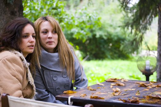 two beautiful woman sitting on table and watching ahead