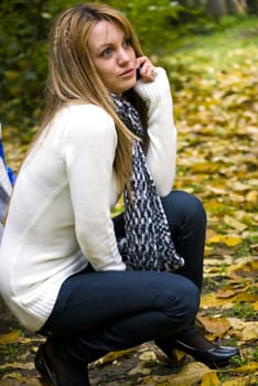 cute blond girl talking on phone outdoors in autumn