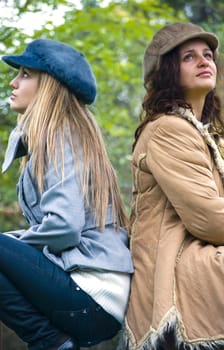 two girls thinking and smiling outdoors in autumn