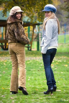 two cute women outdoors in autumn walking and looking back