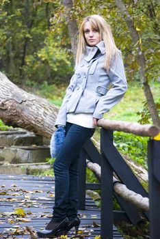 girl posing on wooden bridge in autumn