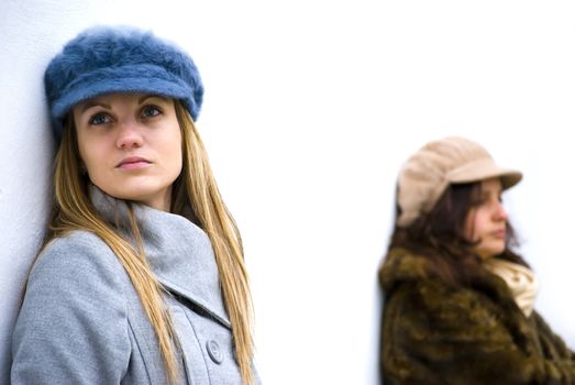 two girls being angry to each other posing on white wall