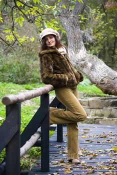 girl posing on wooden bridge in autumn