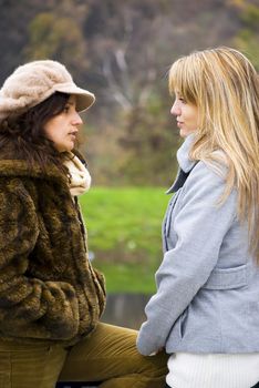 two cute girls talking in a park autumn