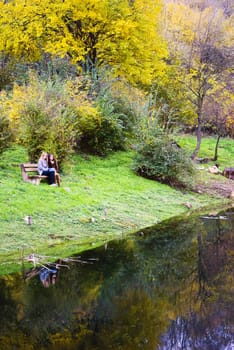 two cute women outdoors in autumn sitting on bench