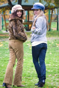 two cute women outdoors in autumn walking and looking back