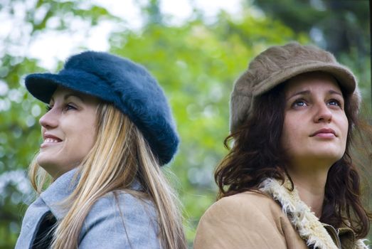 two girls thinking and smiling outdoors in autumn