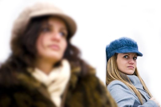 two girls being angry to each other posing on white wall