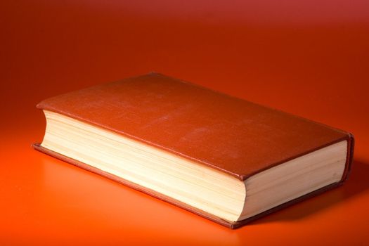 Old book with red cover on a red background