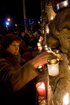 RIGA, LATVIA - NOVEMBER 11: Soldiers Memorial Day. Woman lights candle at Prezident's castle wall to commemorate victory over the Russian and German militia. This victory was important in the birth of Latvia as an independent nation. November 11, 2009 in Riga