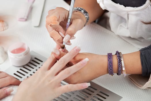 Beautician applying gel on fingernails. Close-up shot