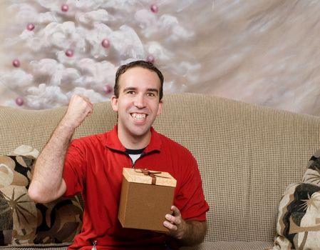 A man wearing red is excited that he got a present for Christmas, with a hand painted holiday tree in the background