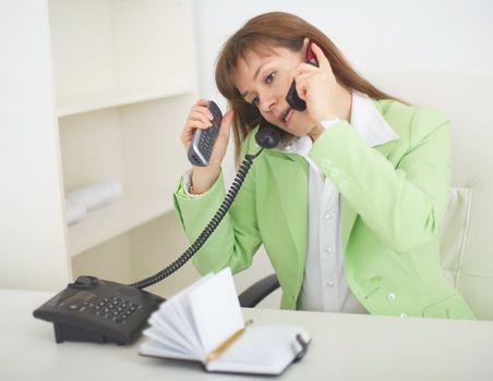 The young woman - the secretary speaks by several phones simultaneously