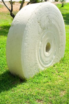 An ancient millstone were located on the grass in the natural background