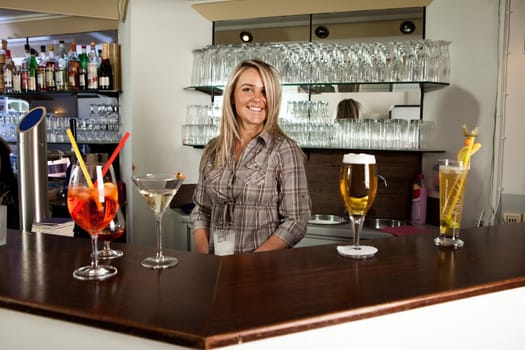 Cheerful bartender standing behind the counter and smiling