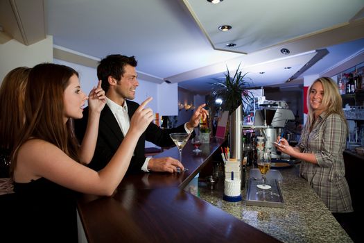 Young people ordering drinks at the bar. Focus on the men