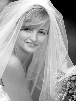 Portrait of smiling young adult bride in veil .