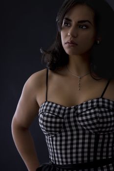Young latino women in black in white dress with checkers motive