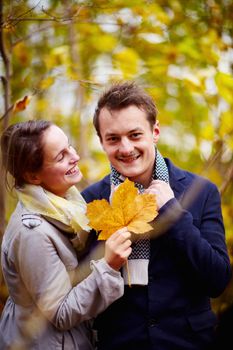 Fall - Cute young couple holding maple leaf in forest