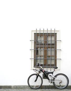 Conceptual shot of a bycicle resting on a white wall.