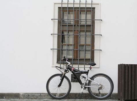 Conceptual shot of a bycicle resting on a white wall.