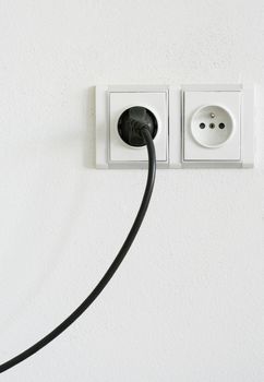 European power outlet with black cord plugged in.