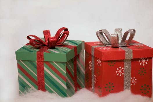 two gifts wrapped in red and green on a white snow background