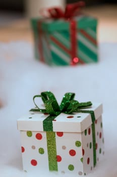 two gifts wrapped in red and green on a white snow background with narrow DOF