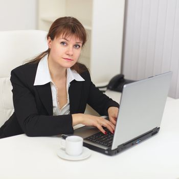 The young beautiful woman with the laptop sits at a table