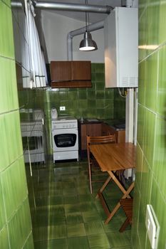 A very small green tiled kitchen and table