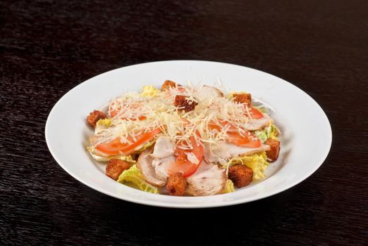Salad of lettuce, chinese cabbage, tomato, garlic rusk, parmesan cheese, sauce and chicken meat