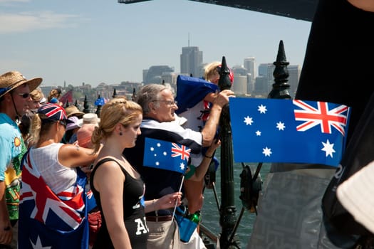 Crowd wearing patriotic clothing and waving Australian flags on Sydney waterfront on Australia Day 2011.