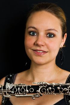 Young beautiful clarinetist woman on black background